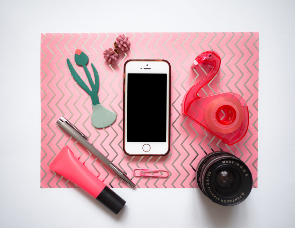 Pinkes Layflat mit Handy, Flamingo-Klebestreifen, Stiften und Kameraobjektiv